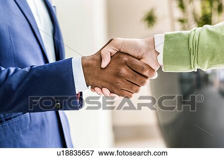 Stock Photo - Close up of businessmen shaking hands outside office building. Fotosearch