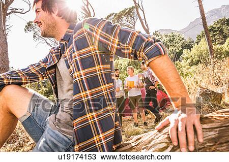 Stock Image - Close up of male camper with friends in forest, Deer Park, Cape Town, South Africa. Fotosearch