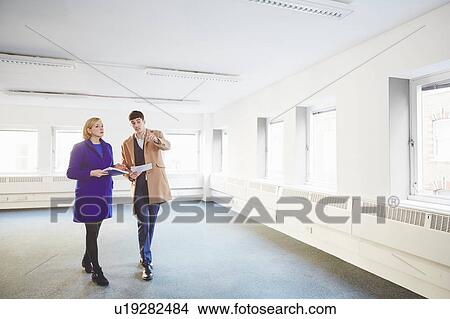 Picture - Colleagues walking through empty office. Fotosearch
