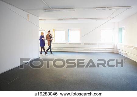 Stock Photograph - Colleagues walking through empty office. Fotosearch
