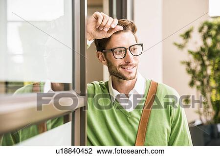 Cool businessman watching whilst leaning against office doorway View Large Photo Image Stock Image - Cool businessman watching whilst leaning against office doorway. Fotosearch