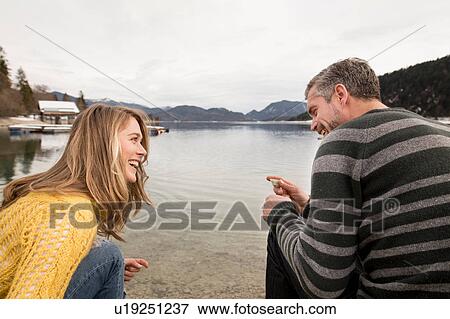 Couple crouching beside lake, smiling, German Alps, Germany View Large Photo Image Stock Photo - Couple crouching beside lake, smiling, German Alps, Germany. Fotosearch