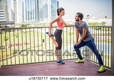 Stock Photo - Couple doing stretch warm up training on balcony, Dubai, United Arab Emirates. Fotosearch