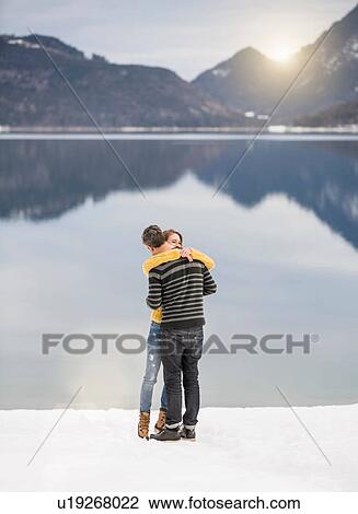 Stock Image - Couple embracing beside lake, German Alps, Germany. Fotosearch