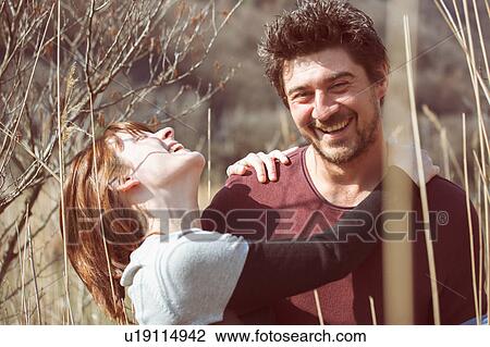Couple in tall grass hugging, smiling View Large Photo Image Stock Image - Couple in tall grass hugging, smiling. Fotosearch