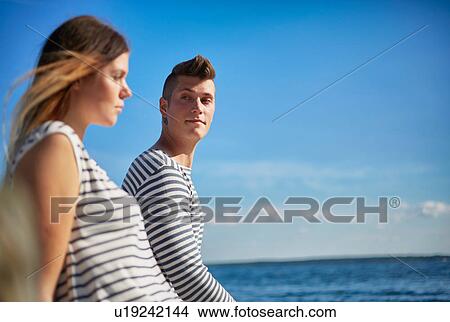 Picture - Couple sitting on wooden pier, relaxing. Fotosearch