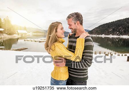 Stock Photography - Couple standing beside lake, embracing, face to face, smiling, German Alps, Germany. Fotosearch