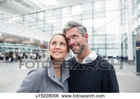 Stock Photograph - Couple standing together at train station, looking up. Fotosearch