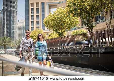 Couple strolling on walkway carrying shopping bags, Dubai, United Arab Emirates View Large Photo Image Stock Photography - Couple strolling on walkway carrying shopping bags, Dubai, United Arab Emirates. Fotosearch