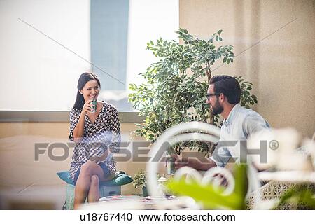 Stock Image - Couple talking and drinking mint tea on hotel room balcony, Dubai, United Arab Emirates. Fotosearch