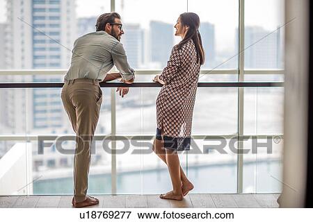 Stock Photo - Couple talking in front of hotel room window, Dubai, United Arab Emirates. Fotosearch