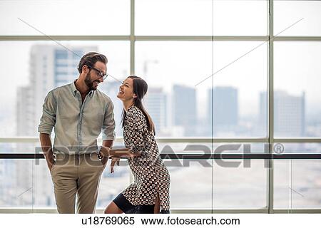Stock Photography - Couple talking in front of hotel room window, Dubai, United Arab Emirates. Fotosearch