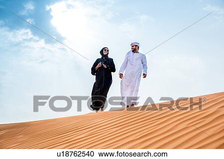 Couple wearing traditional middle eastern clothes walking on desert dune, Dubai, United Arab Emirates View Large Photo Image Stock Image - Couple wearing traditional middle eastern clothes walking on desert dune, Dubai, United Arab Emirates. Fotosearch
