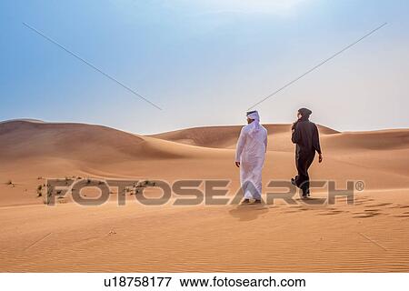 Couple wearing traditional middle eastern clothes walking in desert, Dubai, United Arab Emirates View Large Photo Image Stock Photo - Couple wearing traditional middle eastern clothes walking in desert, Dubai, United Arab Emirates. Fotosearch