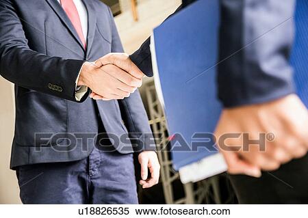 Stock Photography - Cropped shot of businessmen shaking hands outside office. Fotosearch