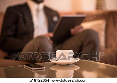 Cropped shot of young businessman sitting on hotel sofa using digital tablet View Large Photo Image Picture - Cropped shot of young businessman sitting on hotel sofa using digital tablet. Fotosearch