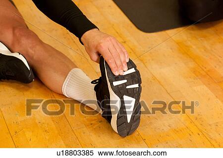 Cropped view of man on wooden floor doing stretching leg exercises View Large Photo Image Stock Photography - Cropped view of man on wooden floor doing stretching leg exercises. Fotosearch