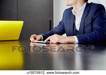 Cropped view of man sitting at desk with digital tablet View Large Photo Image Stock Image - Cropped view of man sitting at desk with digital tablet. Fotosearch