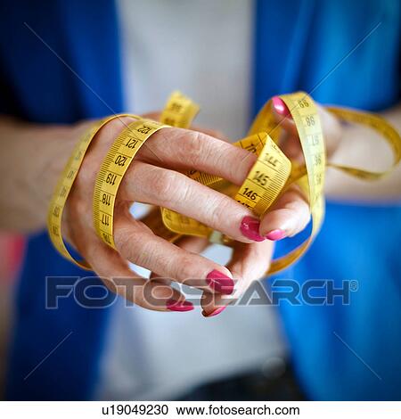 Stock Image - Cropped view of woman hands holding tape measure. Fotosearch