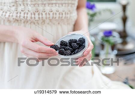 Stock Photo - Cropped view of woman holding bowl of raspberries. Fotosearch