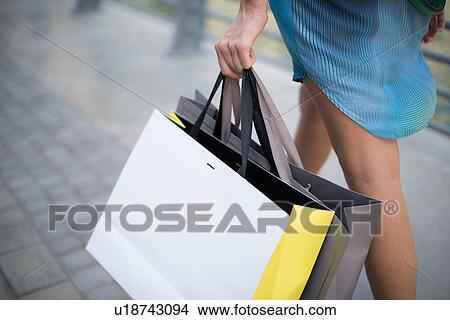Picture - Cropped view of woman strolling on waterfront carrying shopping bags, Dubai, United Arab Emirates. Fotosearch