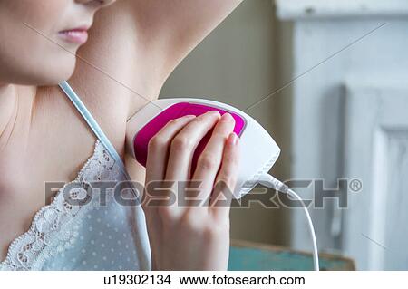 Picture - Cropped view of woman using electric shaver to shave armpit. Fotosearch