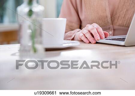 Stock Image - Cropped view of woman using laptop. Fotosearch