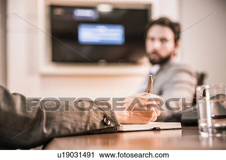 Stock Image - Cropped view of womans hand writing in notebook in business meeting. Fotosearch