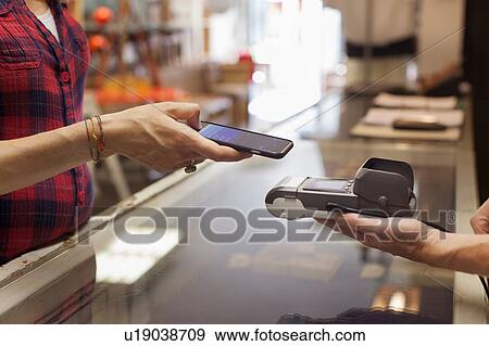 Cropped view of womans hands using smartphone to make contactless payment on smartphone View Large Photo Image Stock Photo - Cropped view of womans hands using smartphone to make contactless payment on smartphone. Fotosearch