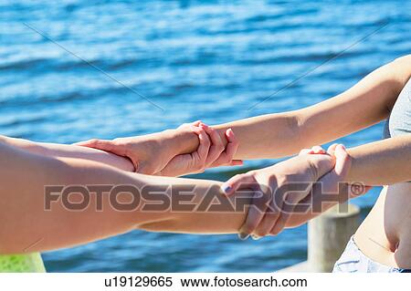 Cropped view of women in front of ocean holding into each others wrists View Large Photo Image Stock Photography - Cropped view of women in front of ocean holding into each others wrists. Fotosearch