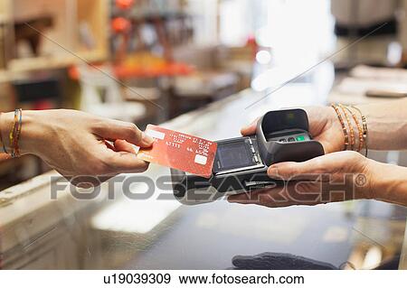 Cropped view of womens hand using credit card to make contactless payment on chip and pin machine View Large Photo Image Stock Photo - Cropped view of womens hand using credit card to make contactless payment on chip and pin machine. Fotosearch