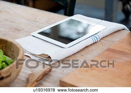 Digital tablet on tea towel on wooden surface View Large Photo Image Stock Photo - Digital tablet on tea towel on wooden surface. Fotosearch