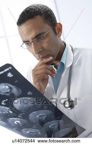 Picture - Doctor examining MRI scans. Fotosearch