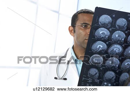 Stock Image - Doctor examining MRI scans. Fotosearch