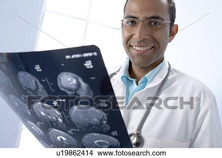 Picture - Doctor holding MRI scans. Fotosearch