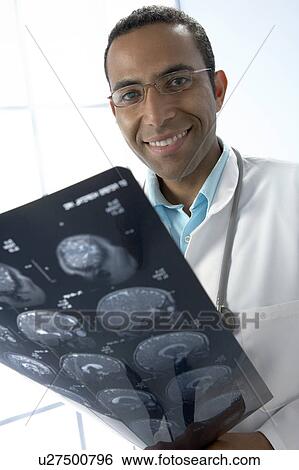 Doctor holding MRI scans View Large Photo Image Stock Photograph - Doctor holding MRI scans. Fotosearch