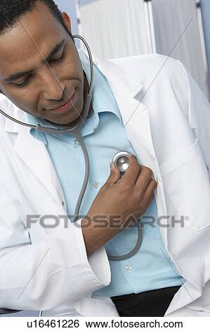 Doctor listening to his heart View Large Photo Image Stock Photograph - Doctor listening to his heart. Fotosearch