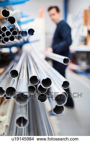 Factory worker removing metal rod from shelf in roller blind factory View Large Photo Image Picture - Factory worker removing metal rod from shelf in roller blind factory. Fotosearch
