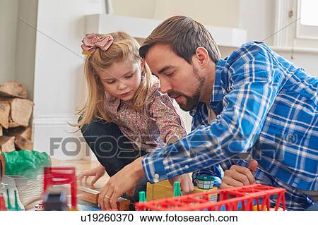 Stock Image - Father and daughter playing with toy train set. Fotosearch