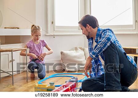 Stock Photo - Father and daughter playing with toy train set. Fotosearch