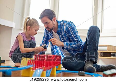 Stock Photography - Father and daughter playing with toy train set. Fotosearch