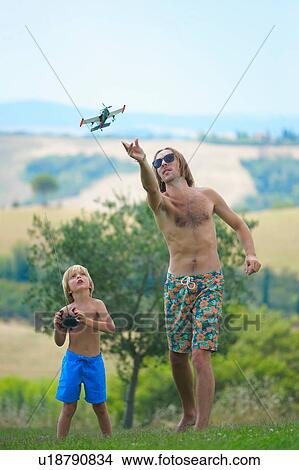 Picture - Father and son flying remote control plane, outdoors. Fotosearch