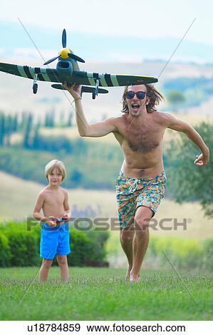 Father and son flying remote control plane, outdoors View Large Photo Image Stock Photo - Father and son flying remote control plane, outdoors. Fotosearch