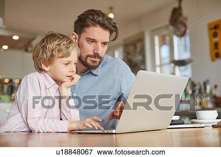 Father and son using laptop in home office View Large Photo Image Stock Photo - Father and son using laptop in home office. Fotosearch
