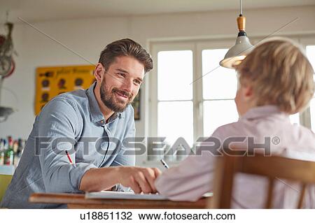 Stock Image - Father and son working in home office. Fotosearch