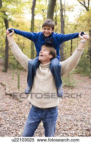 Stock Photography - Father carrying his son in a wood. Fotosearch