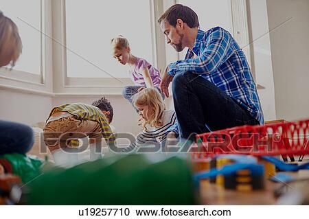 Father watching children play, low angle view View Large Photo Image Stock Image - Father watching children play, low angle view. Fotosearch