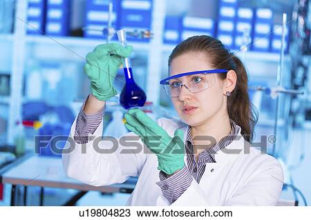 Stock Image - Female chemist holding flask. Fotosearch