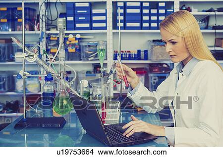 Picture - Female chemist working on a laptop. Fotosearch