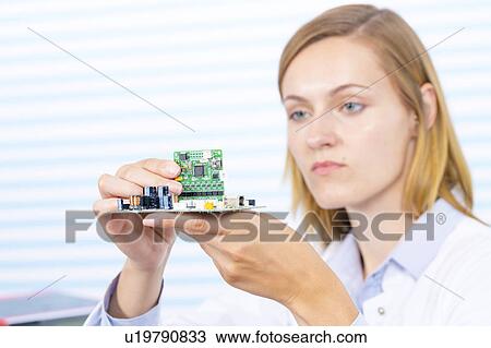Stock Image - Female electrical engineer fixing circuit. Fotosearch